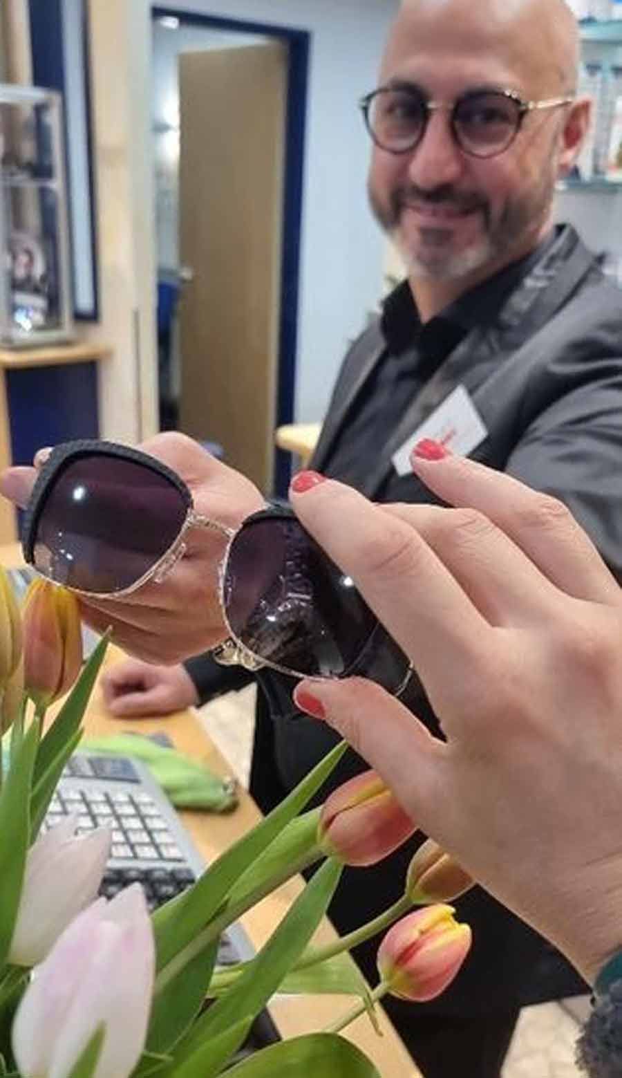 eine Frau hält ein Paar Sonnenbrille vor einem Mann mit Brille .
