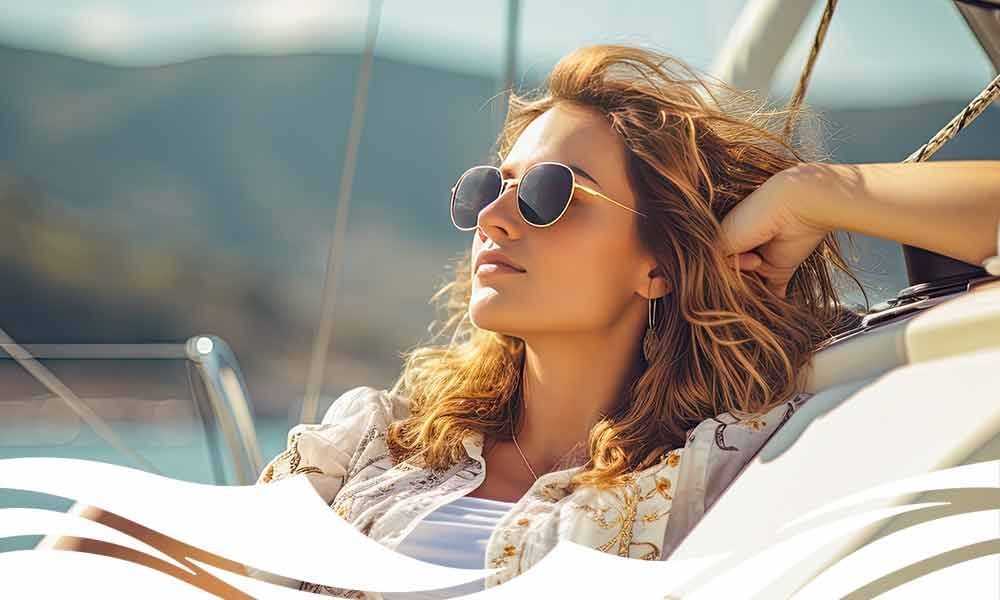 Eine Frau trägt Sonnenbrille und sitzt auf einem Boot .