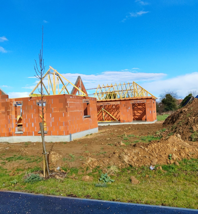 Une maison en brique en construction avec un toit en bois