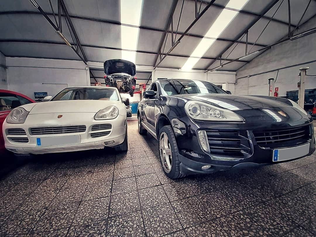Dos coches deportivos aparcados en un luminoso garaje cubierto, un cupé blanco junto a un cupé negro.