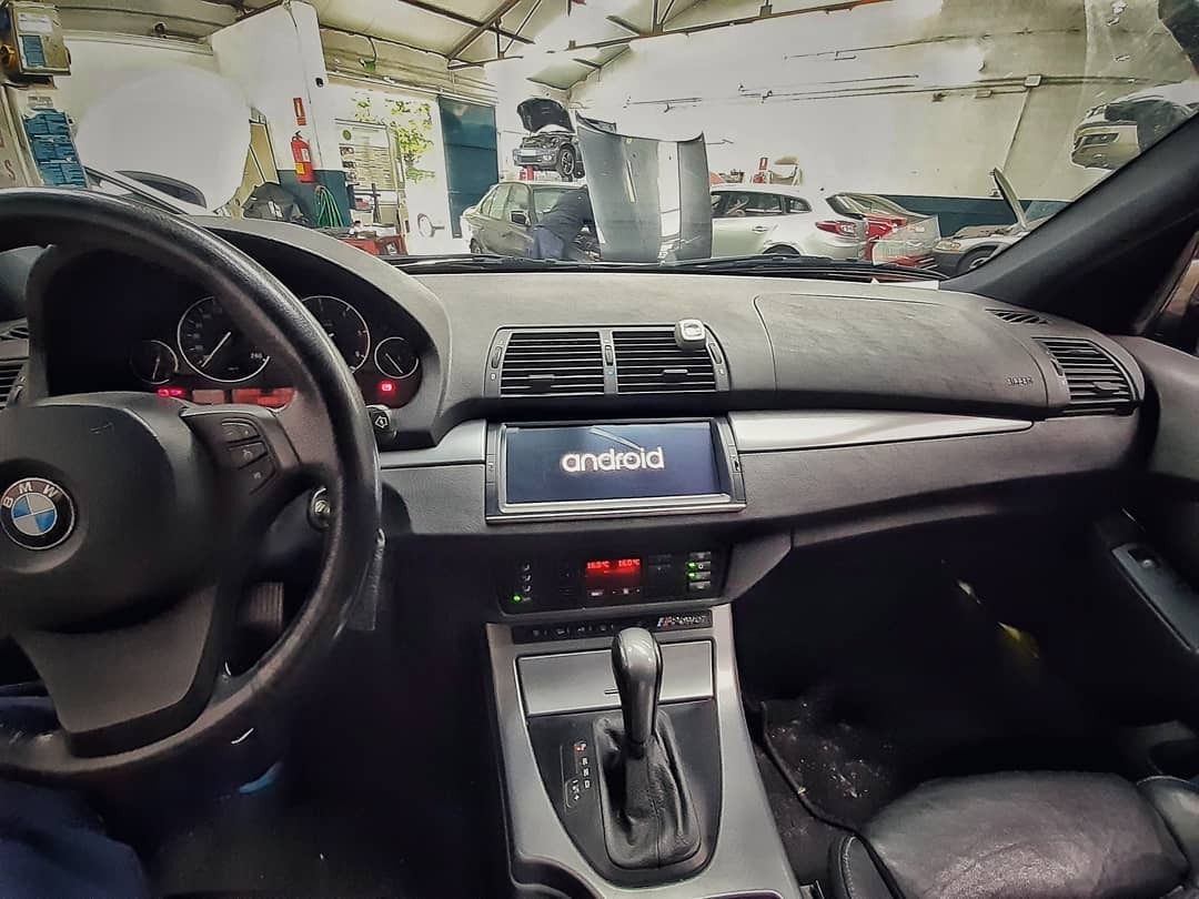 Interior de un automóvil BMW, donde se aprecian el volante, el tablero y la consola central en un garaje.