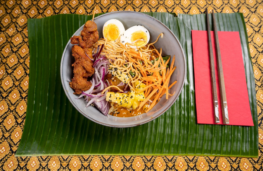 Khao Soi angerichtet in einer Schüssel mit Stäbchen auf einer roten Serviette im Thai Restaurant Zug.