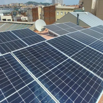 Paneles solares en la azotea junto a una antena parabólica, con vistas a la ciudad bajo un cielo despejado