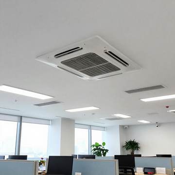 Interior de oficina luminoso y moderno, con escritorios, monitores, rejillas de ventilación en el techo y grandes ventanas