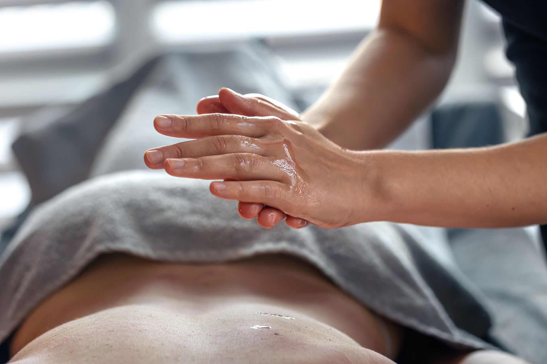 Mains appliquant de l'huile sur le dos d'une personne