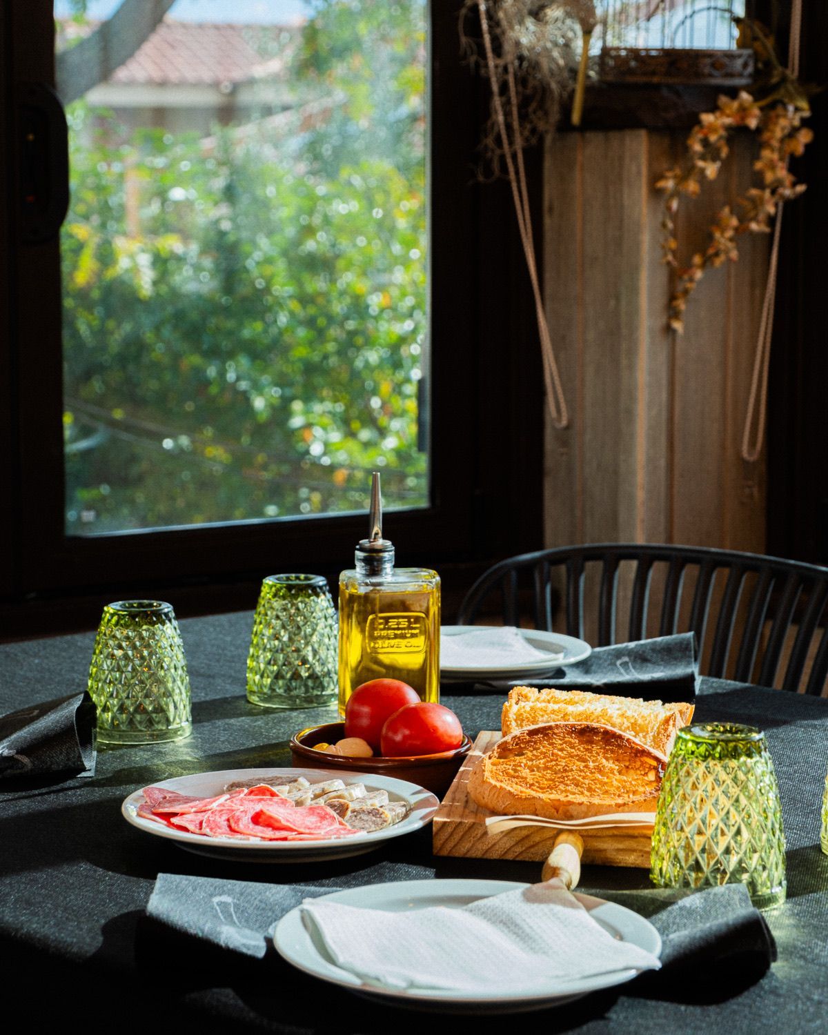 Una mesa con platos, vasos y una botella de aceite encima.