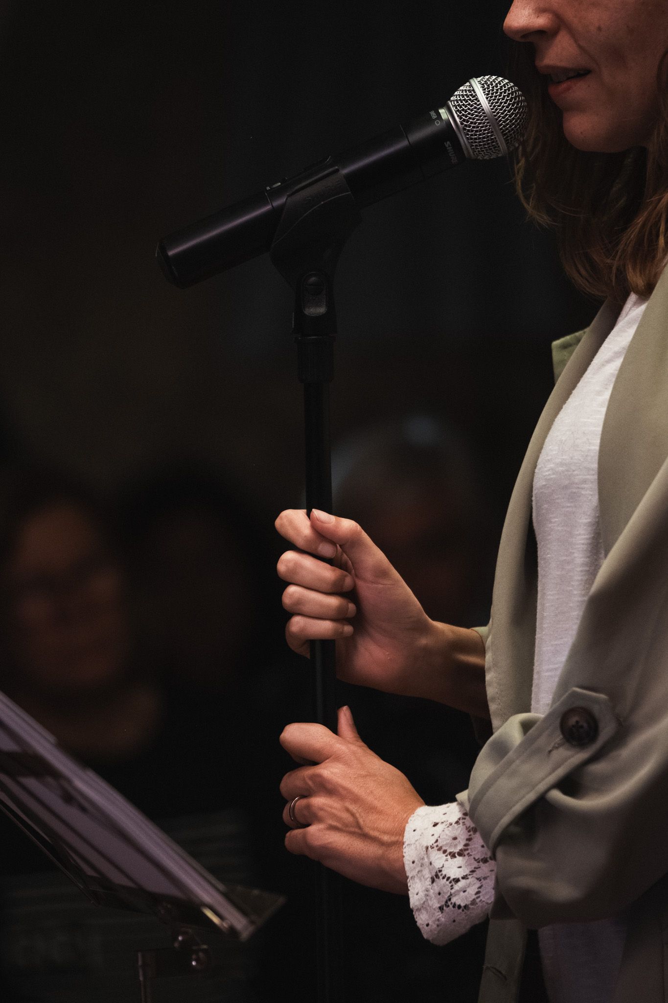 Una mujer está cantando con un micrófono en una habitación oscura.