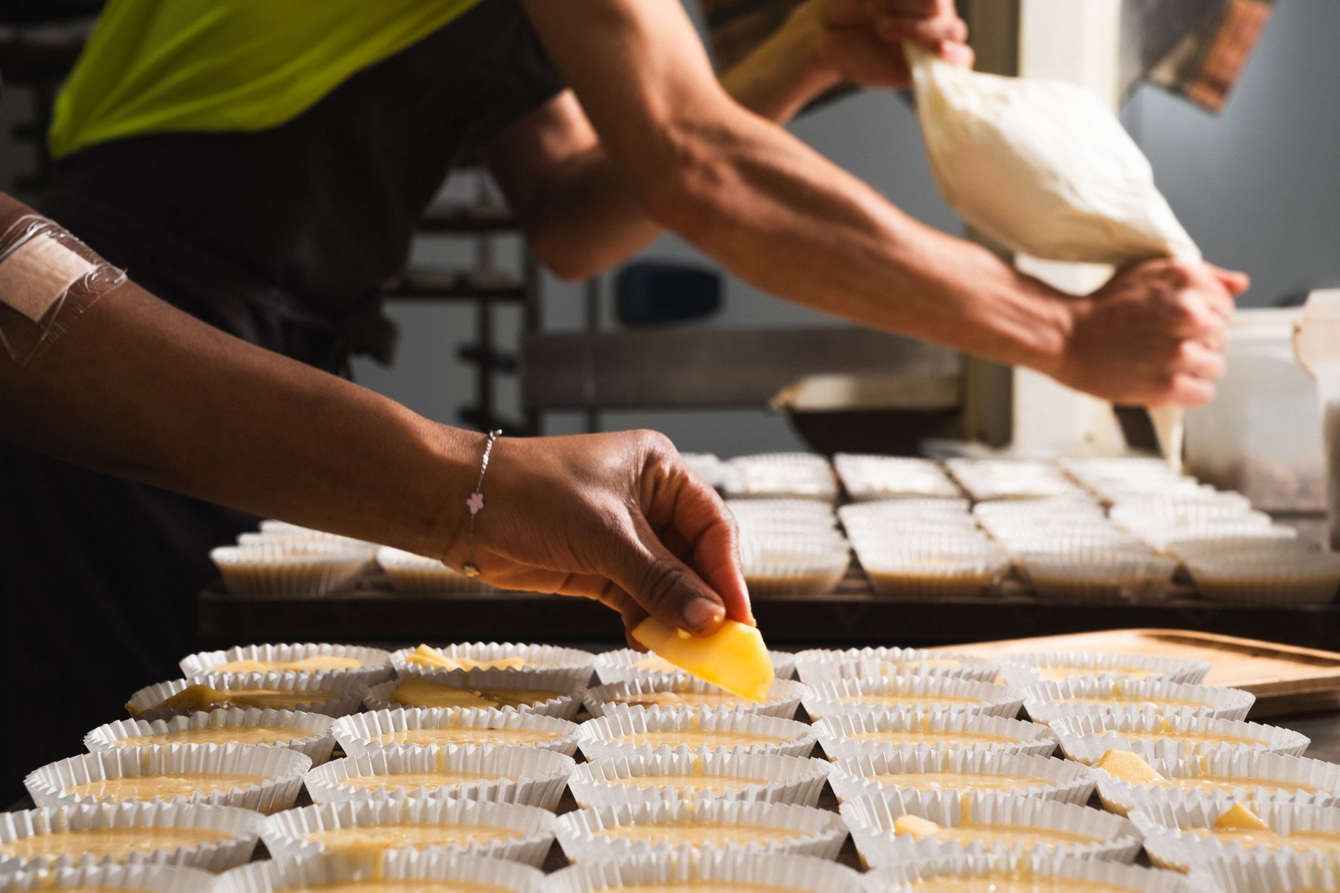 Una persona está decorando cupcakes en una panadería.