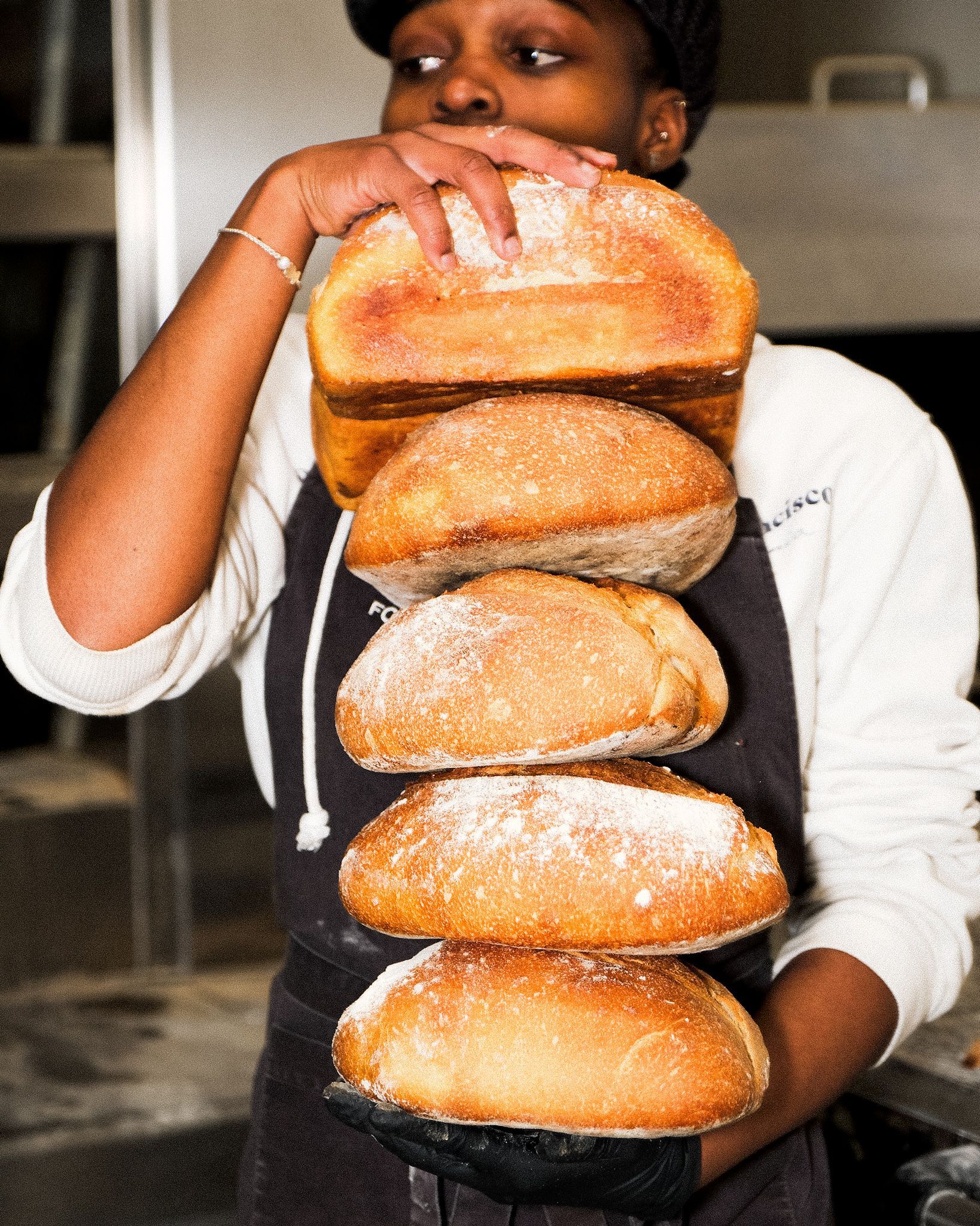Un hombre sostiene una pila de pan en sus manos.