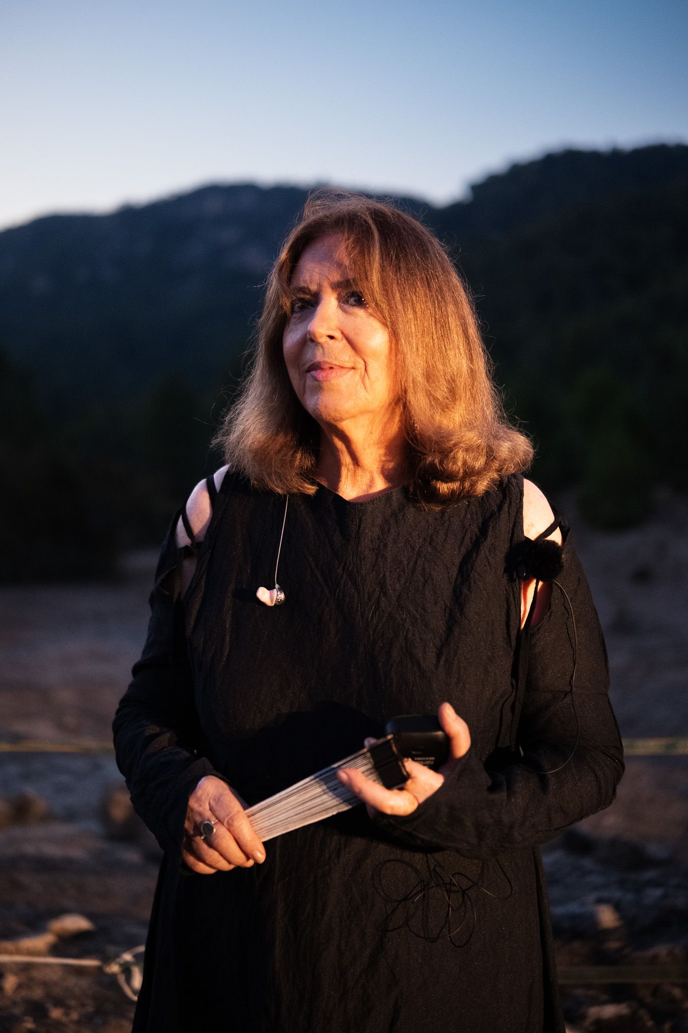 Una mujer con un vestido negro sostiene una guitarra en sus manos.