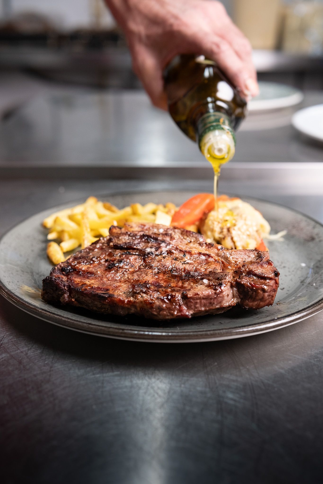 Una persona está vertiendo aceite sobre un filete en un plato.