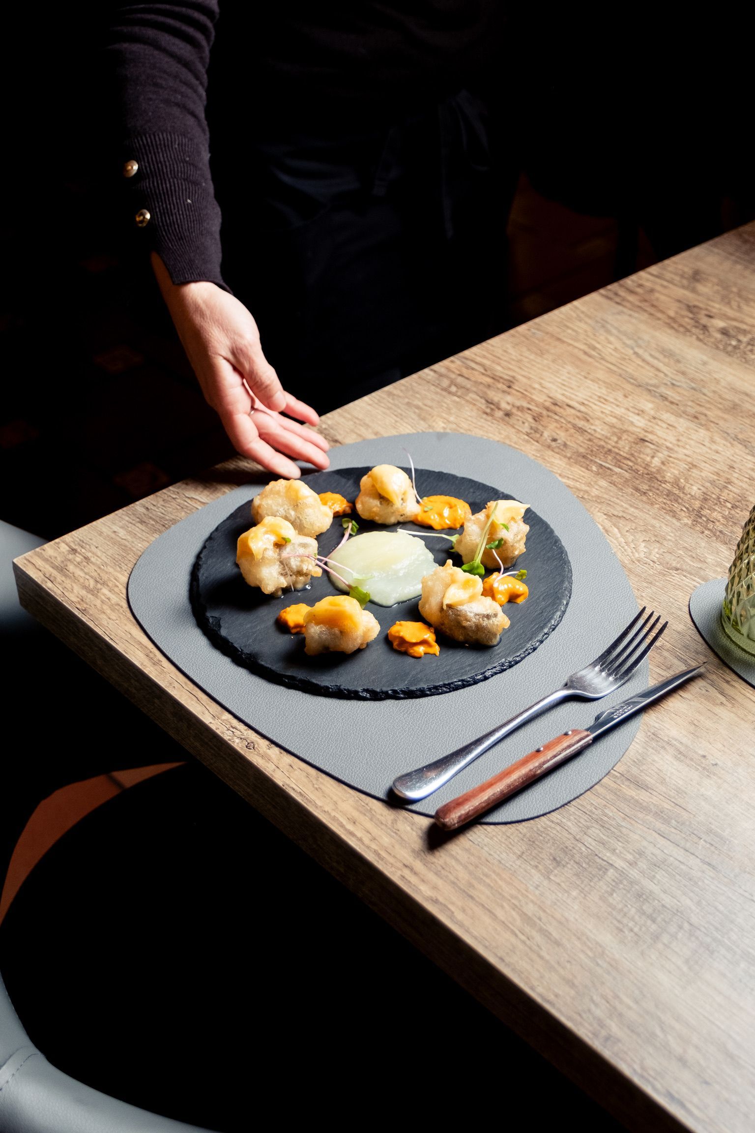Una persona está poniendo un plato de comida en una mesa.