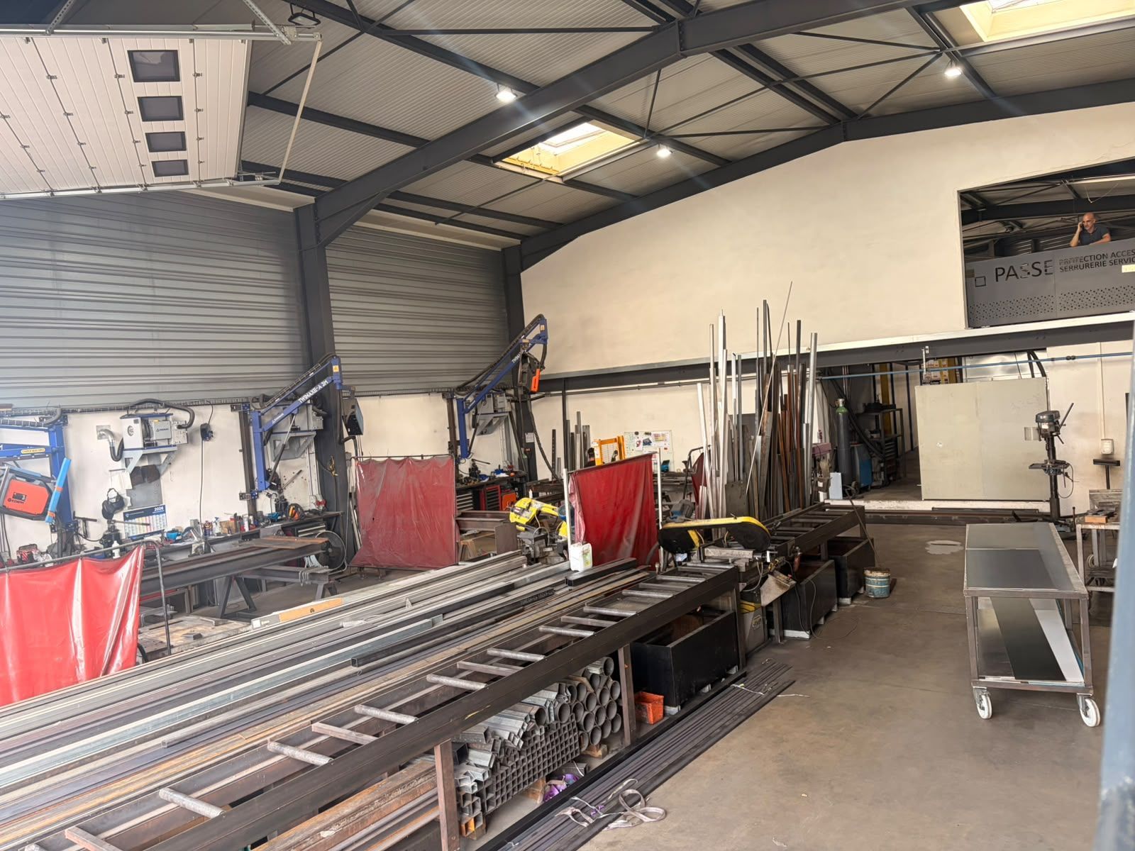 Atelier industriel avec étagères métalliques, outils et équipements à l'intérieur d'un grand garage