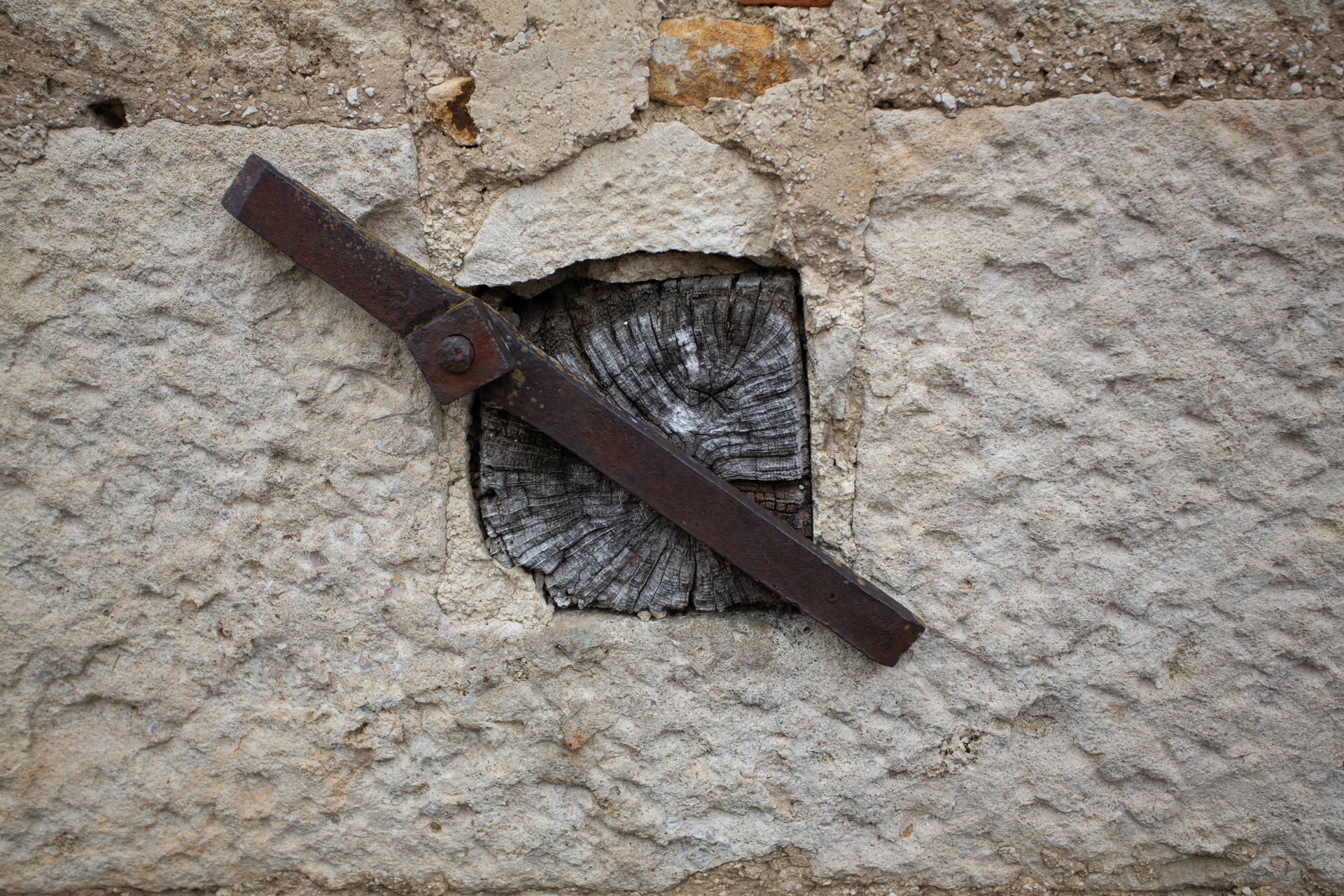 Loquet en métal rouillé sur un mur de pierre brute au-dessus d'une petite ouverture brisée
