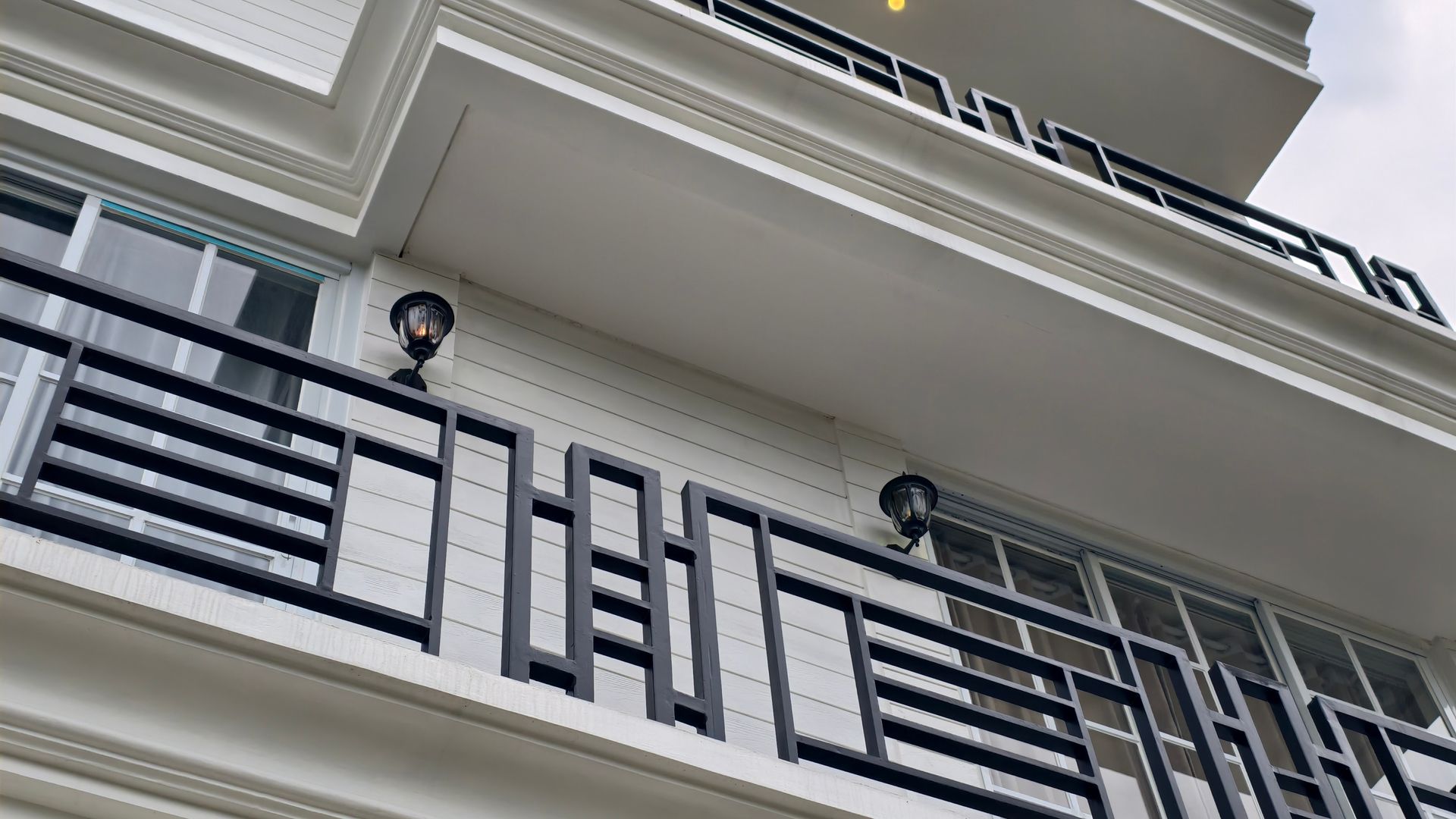 Balcon d'appartement moderne blanc avec rambardes en métal noir et appliques murales