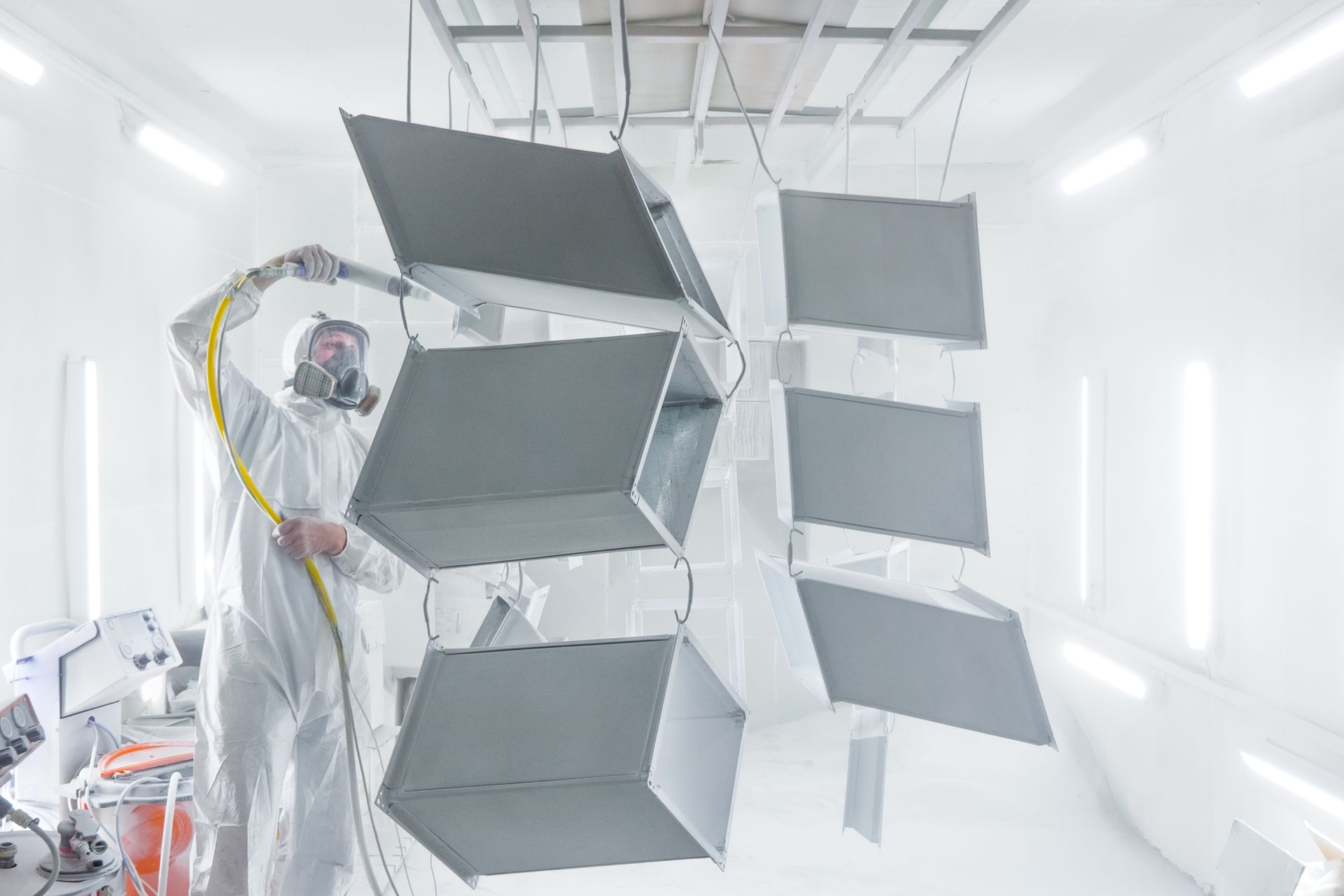 Personne dans une cabine de peinture blanche utilisant un système de peinture suspendu à panneaux multiples