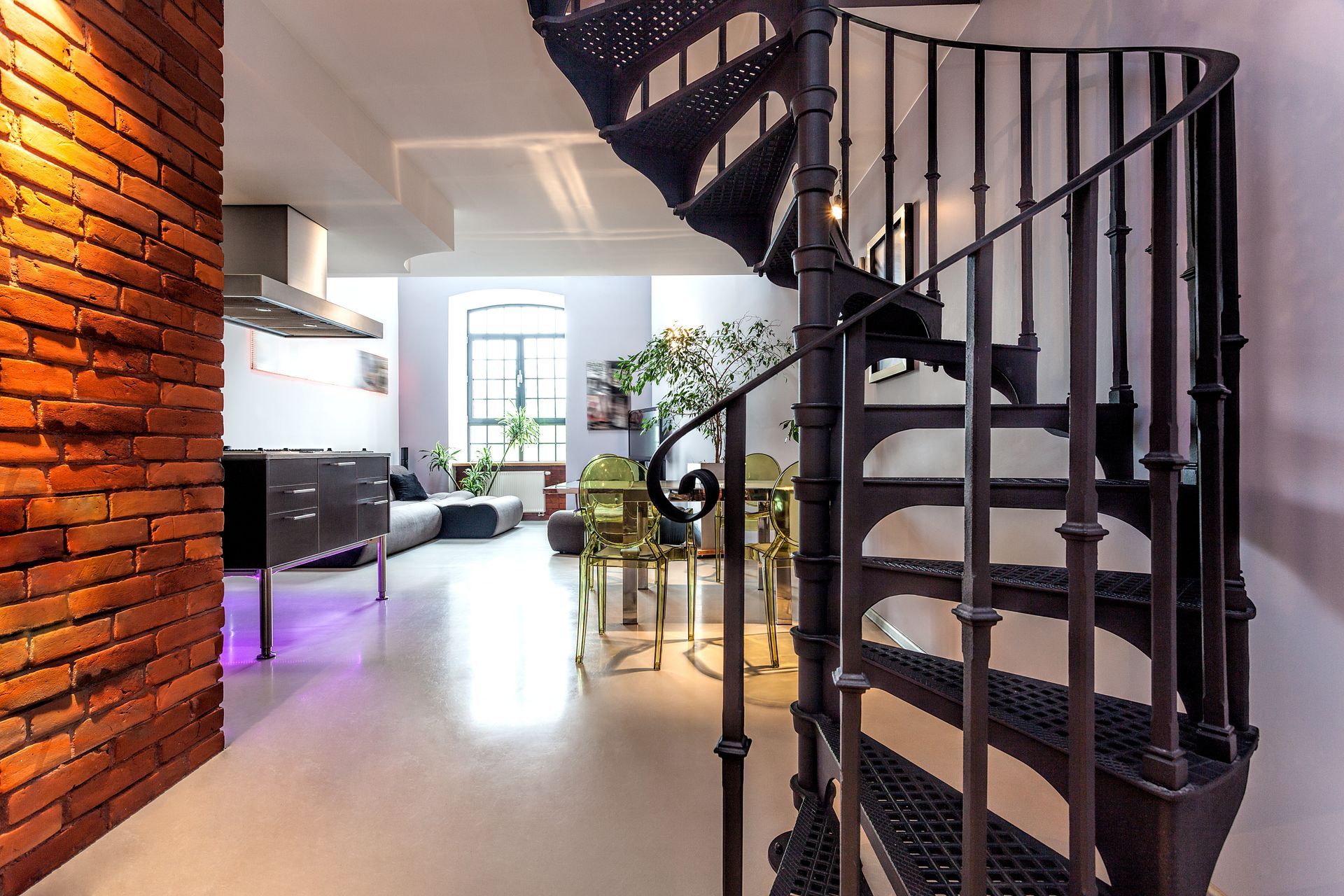 Intérieur moderne à aire ouverte avec un escalier en colimaçon, un mur de briques apparentes et un espace de vie lumineux
