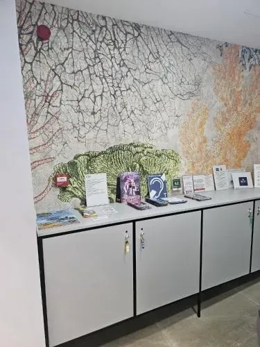 Gabinetes blancos con elementos en la parte superior contra un mural de pared colorido.