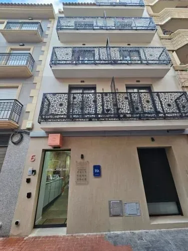 Exterior de edificio de apartamentos, fachada beige, balcones de hierro forjado negro. 