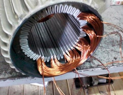 Bobinas de alambre de cobre enrolladas alrededor de un estator de motor metálico dañado.
