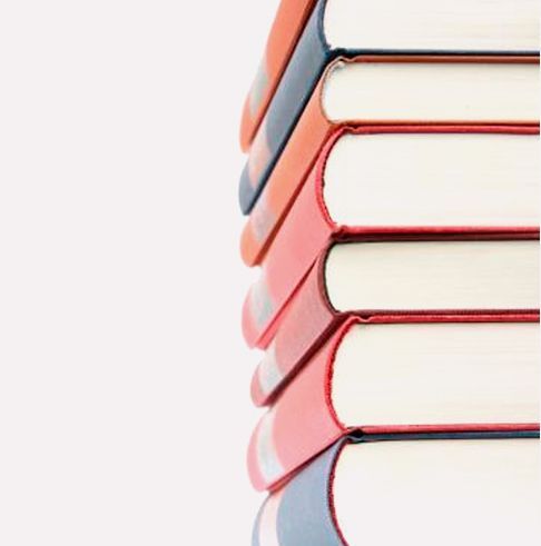 Pila de libros de tapa dura de colores sobre un fondo blanco.