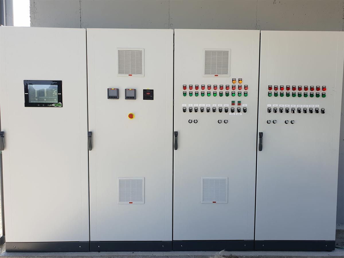 Paneles de control eléctrico industrial alineados, armarios blancos con luces indicadoras e interruptores.