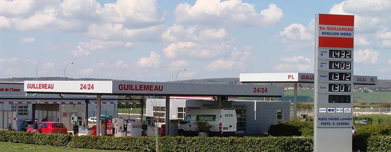 Station-service avec affichage des prix ; signalétique rouge et blanche.