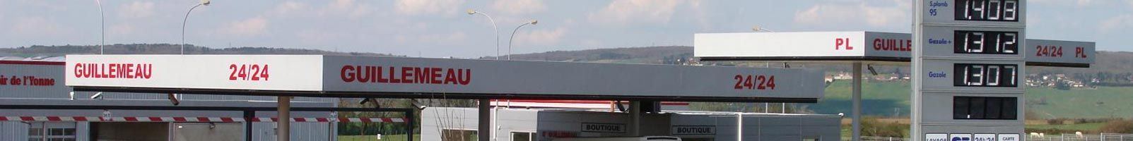 Station-service avec enseignes rouges. Panneau d'affichage des prix en arrière-plan.