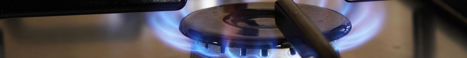 Flammes bleues entourant un objet circulaire, probablement un brûleur ou un élément chauffant, à l'intérieur.