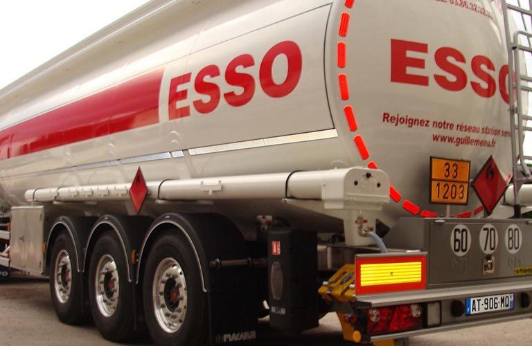 Camion-citerne Esso blanc avec des touches de rouge, transportant des liquides inflammables. L'étiquette indique les codes de danger.