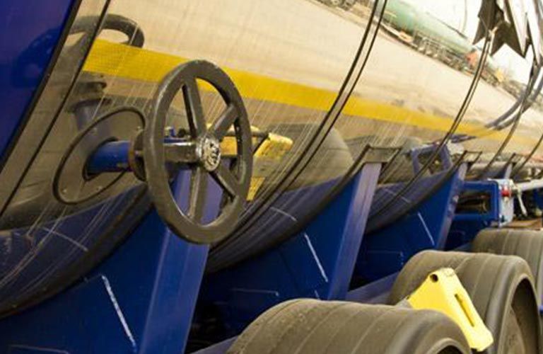 Camion-citerne argenté avec une roue à valve noire, soutenu par des supports bleus, reposant sur des pneus.