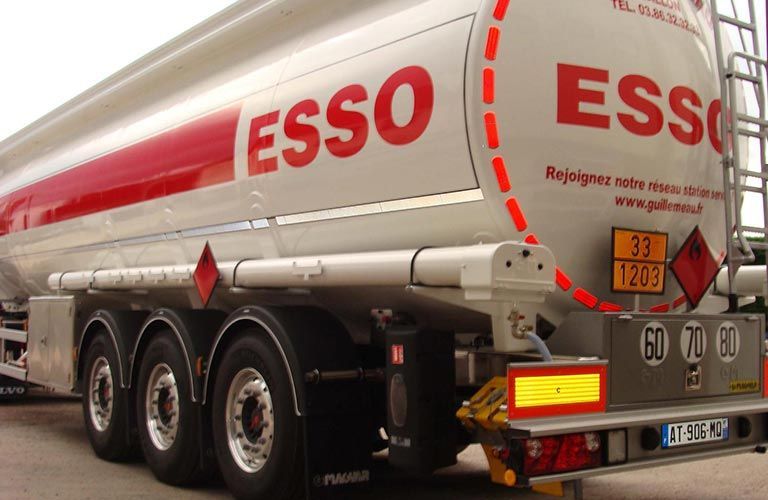 Camion-citerne avec logo « Esso », bandes rouges et panneaux de signalisation de danger.