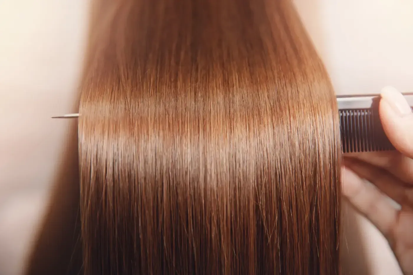 Una mujer se peina su largo cabello castaño con un peine.