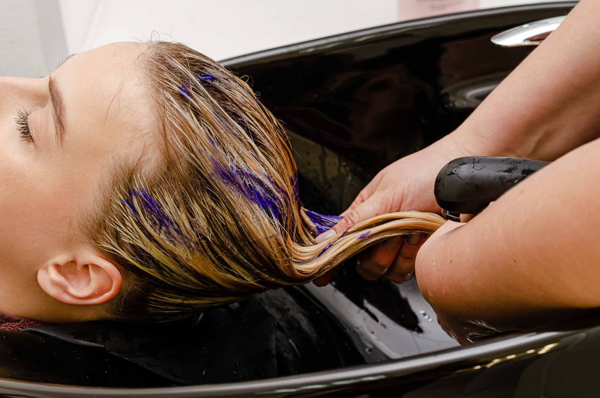 Una mujer se está lavando el cabello en un lavabo.