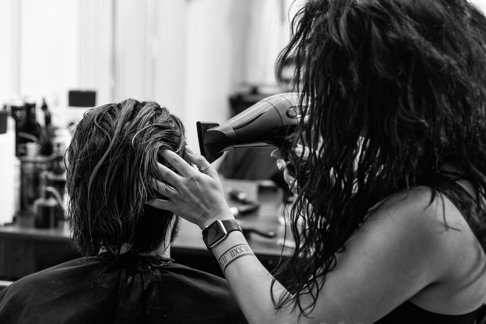 Una mujer está secando el cabello de otra mujer en una fotografía en blanco y negro.