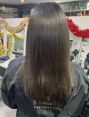 Una mujer se está alisando el cabello en una peluquería.