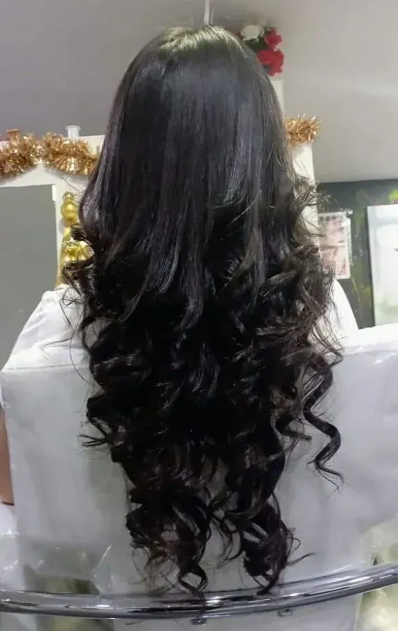 Una mujer con cabello largo y negro está sentada en una silla.