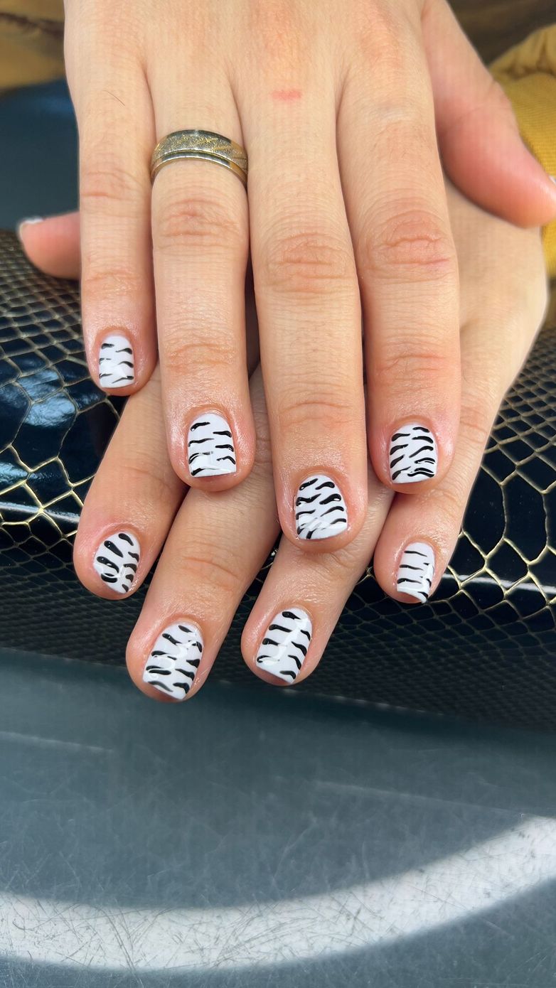 Un primer plano de las uñas de una persona con un diseño de estampado de cebra.