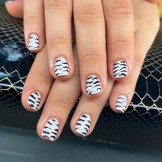 Un primer plano de las uñas de una persona con un diseño de estampado de cebra.
