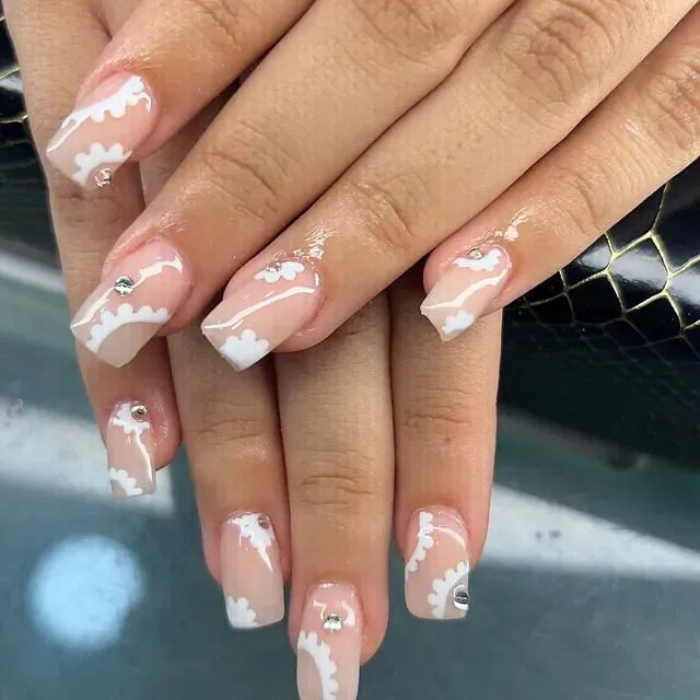 Un primer plano de las uñas de una mujer con diseños blancos.