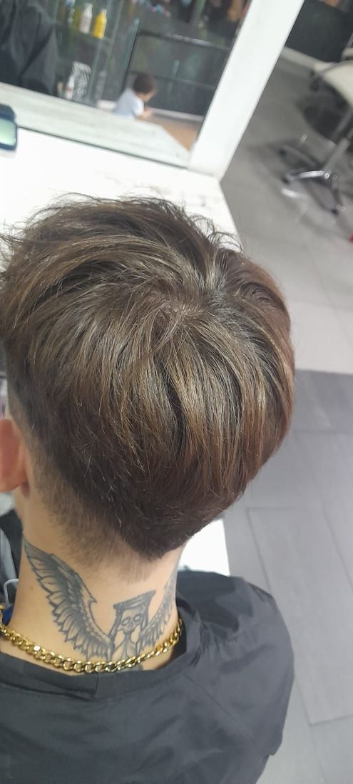 Un hombre con un tatuaje en el cuello se está cortando el pelo en una peluquería.