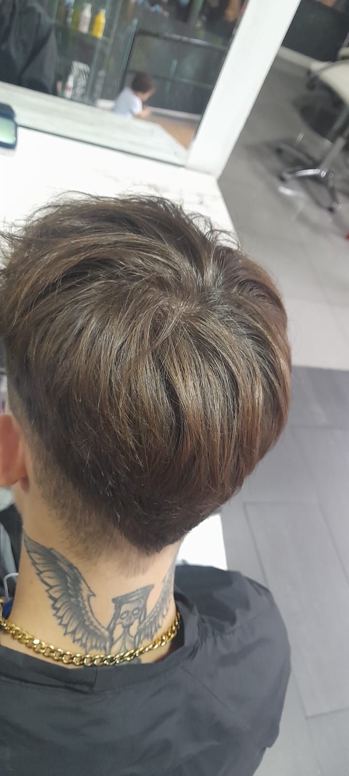 Un hombre con un tatuaje en el cuello se está cortando el pelo en una peluquería.