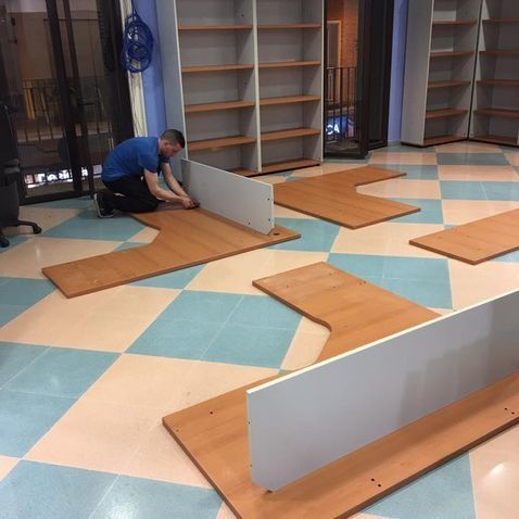 Un hombre ensambla componentes de escritorio en una habitación con estanterías.