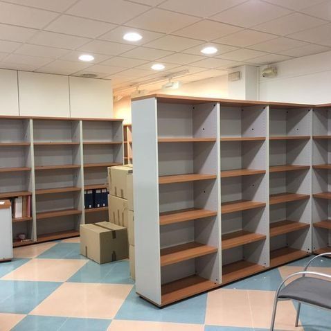 Espacio de oficina vacío con estantes blancos y marrones, piso a cuadros y cajas.