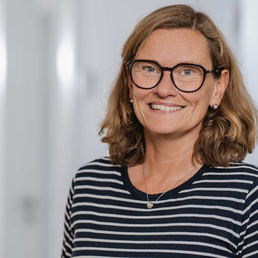 eine Frau mit Brille lächelt in einem Schwarz-Weiß-Foto .