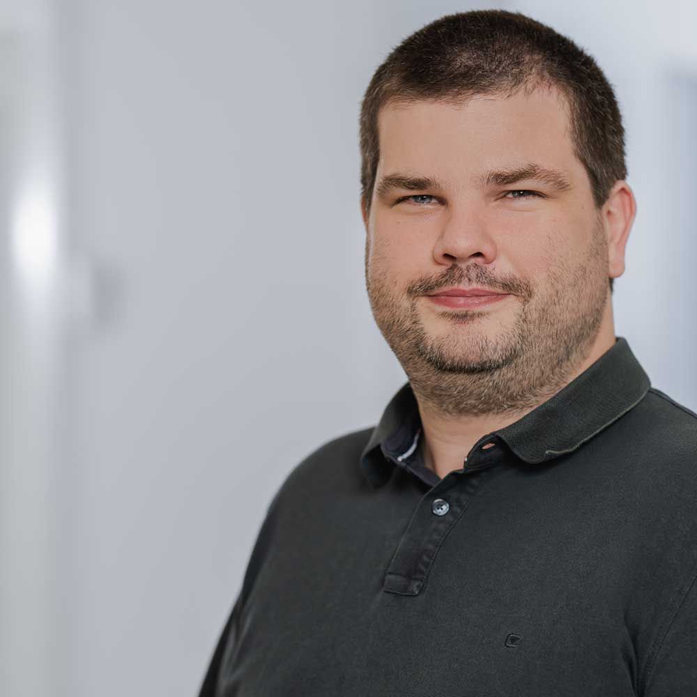 ein Mann in einem gestreiften Hemd steht vor einer Gruppe von Menschen