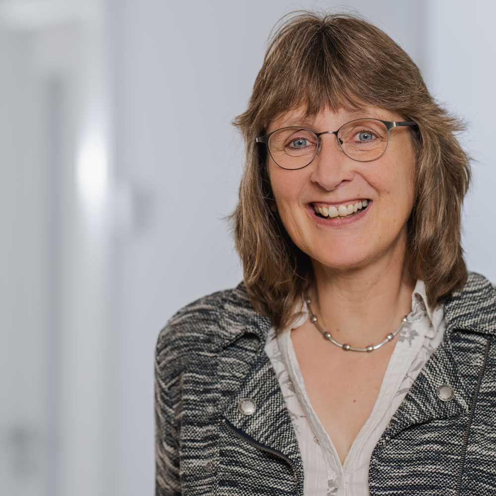 eine Frau mit Brille lächelt in einer Schwarz-Weiß-Fotografie .