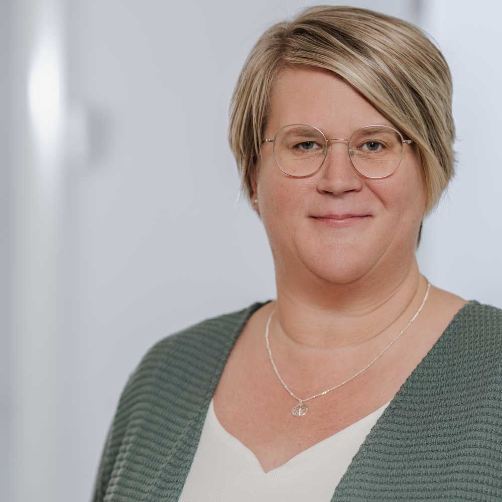 eine Frau mit Brille und Schal lächelt in einem Schwarz-Weiß-Foto .