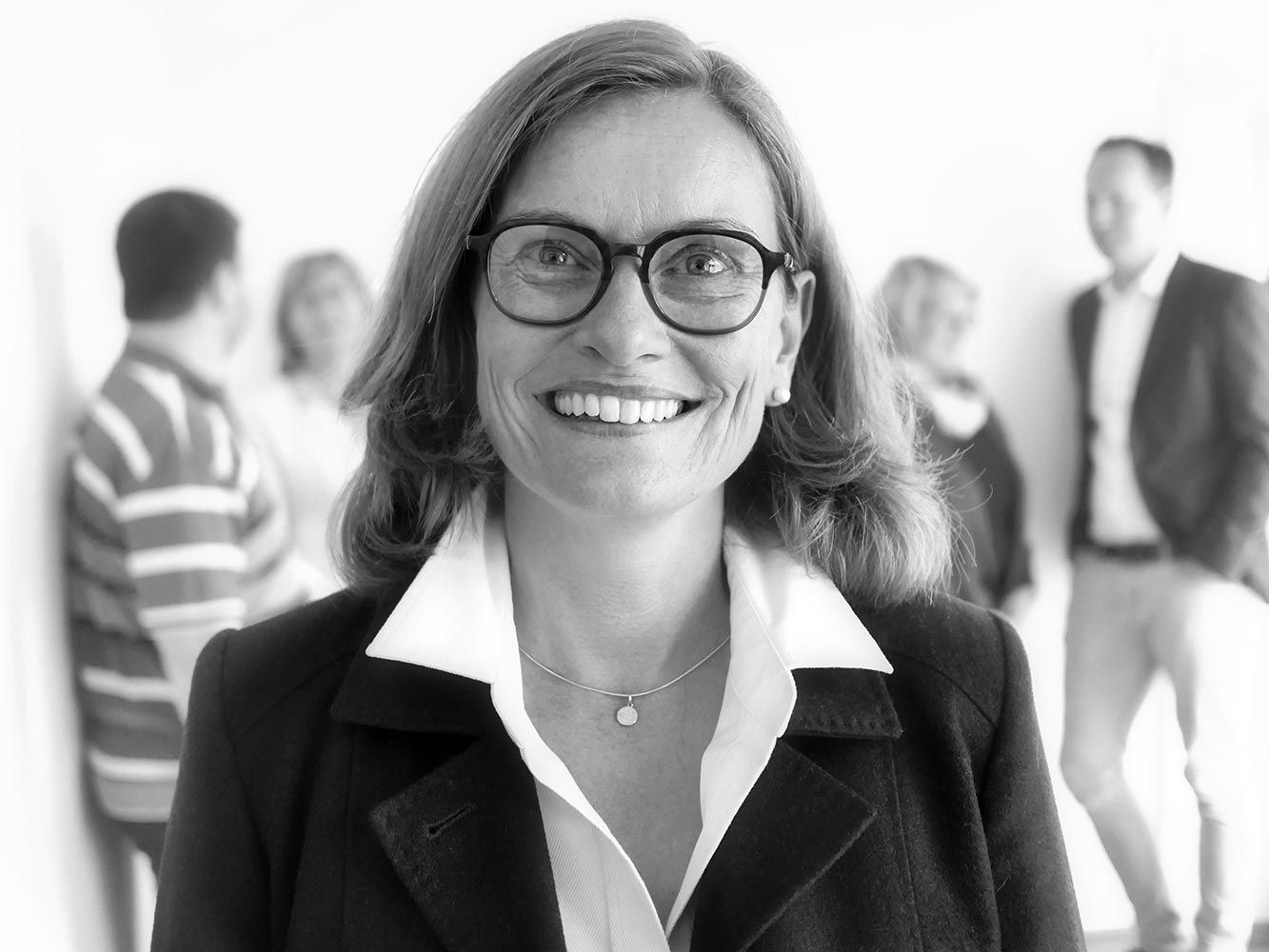 eine Frau mit Brille lächelt in einem Schwarz-Weiß-Foto .