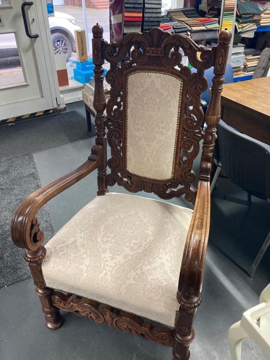 Dunkler Holzstuhl mit Verzierungen und heller Polsterung